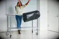 A person throws the Osprey Transporter Waterproof Duffel 70L off of a metal table