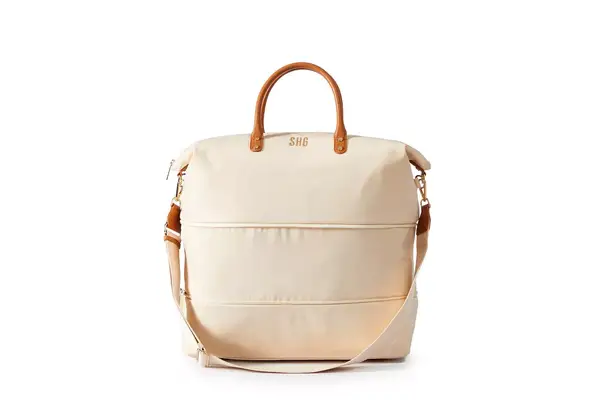 A person packs the Mark & Graham Terminal 1 Checked Rolling Duffle Bag