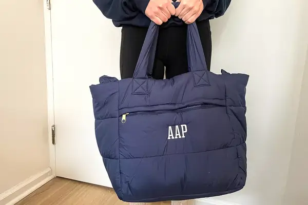 A person holds a navy puffer tote bag