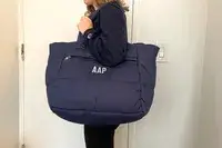 A person holds a navy puffer tote bag