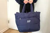 A person holds a navy puffer tote bag