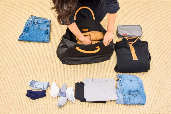 A person packs the Mark & Graham Terminal 1 Expandable Travel Tote