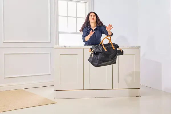 A person throws the Mark & Graham Terminal 1 Expandable Travel Tote off of a table