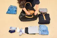 A person packs the Mark & Graham Terminal 1 Expandable Travel Tote