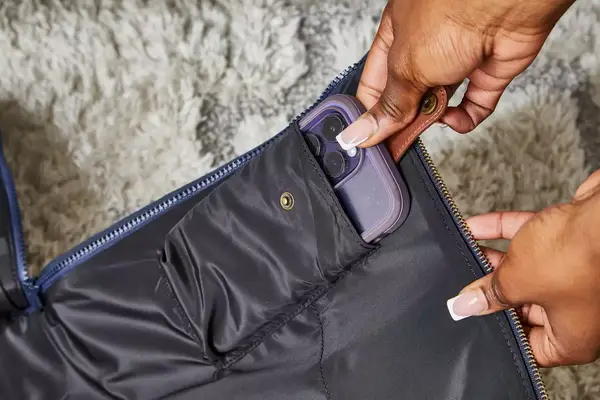 Hands putting a phone into the Mark & Graham Commuter 2-in-1 Garment Bag