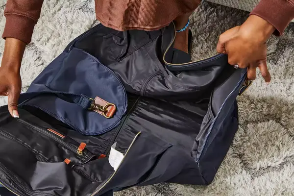 Hands opening the Mark & Graham Commuter 2-in-1 Garment Bag