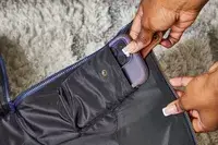 Hands putting a phone into the Mark & Graham Commuter 2-in-1 Garment Bag