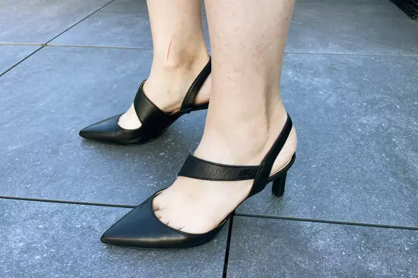 A person wearing the Calvin Klein Larin Pump on outdoor tiled flooring