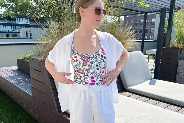 A person standing on a rooftop patio wearing sunglasses and casual attire