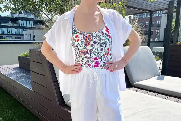 Person wearing floral patterned top with white pants in an outdoor seating area