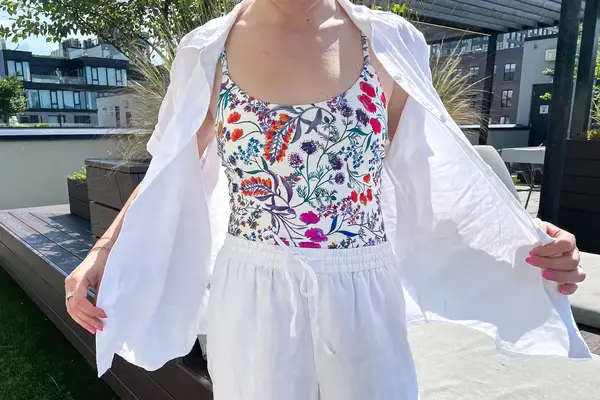 A person wearing a floralpatterned top and white clothing outdoors