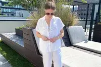 A person standing outdoors in a relaxed patio setting wearing sunglasses and casual attire