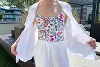 A person wearing a floralpatterned top and white clothing outdoors