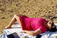 Woman lies on the sand wearing a CupShe Crochet Mini Dress