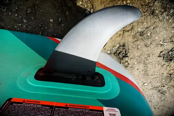 A person standing on the Atoll 11-foot Inflatable Stand-up Paddle Board while paddling on a lake