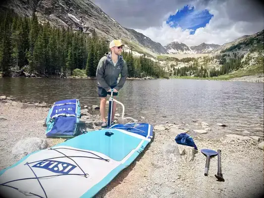 Peron pumping up Isle Pioneer 2.0 Inflatable Stand Up Paddle Board by lake