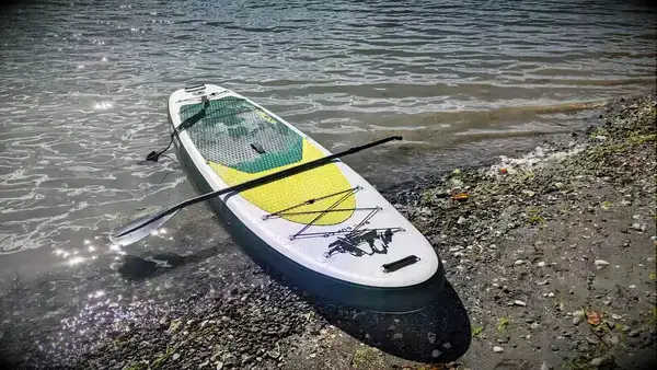 ROC Inflatable Stand Up Paddle Board halfway in the water with the paddle on top