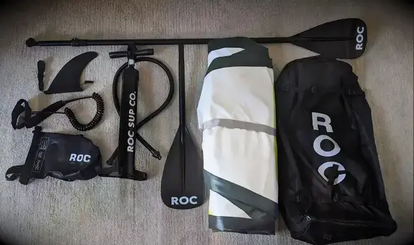 ROC Inflatable Stand-up Paddle Board deflated on a floor with its accessories