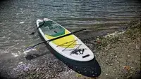 ROC Inflatable Stand Up Paddle Board halfway in the water with the paddle on top