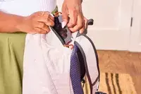 A person places a cell phone into the Bellroy Lite Daypack