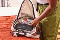 A person places travel items into the Bellroy Lite Daypack