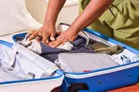 A person places the Bellroy Lite Daypack into a suitcase