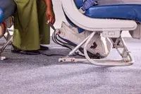 A person places the Bellroy Lite Daypack under the seat in front of them