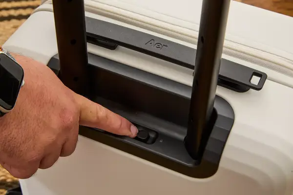 A finger touching a switch on the Aer Carry-On Max