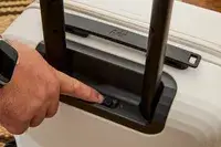 A finger touching a switch on the Aer Carry-On Max