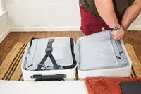 A person zippering the Aer Carry-On Max closed on the inside