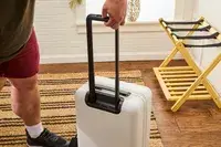 A hand holding the handle of the Aer Carry-On Max