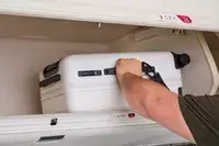 A person placing the Aer Carry-On Max into an overhead bin