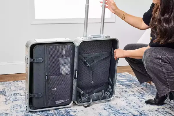 A person examines the Away The Carry-on Aluminum Edition