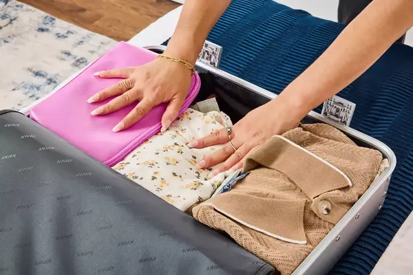 A person packs clothing into the Away The Carry-on Aluminum Edition