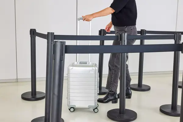 A person wheels the Away The Carry-on Aluminum Edition over a linoleum floor