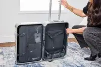 A person examines the Away The Carry-on Aluminum Edition