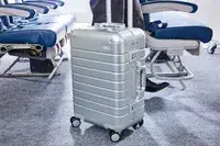 A person wheels the Away The Carry-on Aluminum Edition over carpet