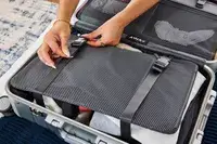 A person secures the straps on the Away The Carry-on Aluminum Edition