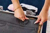 A person secures the strap on the Away The Carry-on Aluminum Edition