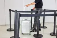 A person wheels the Away The Carry-on Aluminum Edition over a linoleum floor