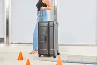 A person wheeling the Briggs & Riley Extra Large Trunk Spinner