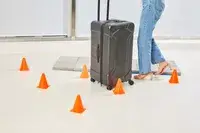 A person wheeling the Briggs & Riley Extra Large Trunk Spinner through orange cones