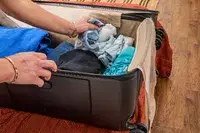 A person placing items into the Briggs & Riley Extra Large Trunk Spinner