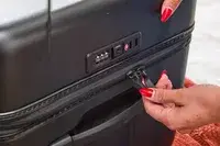 Two hands holding the zippers of the Briggs & Riley Extra Large Trunk Spinner