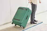 Person rolling the Samsonite Elevation Plus Large Softside Spinner on pavers