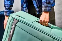 Hand holding the side handle of the Samsonite Elevation Plus Large Softside Spinner