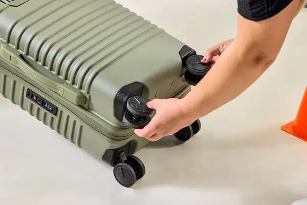 A person touches the wheels on the Béis The Small Carry-on Roller