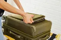 A person sliding a laptop into the Dagne Doverr Seattle Carry On Rolling Luggage 20.5