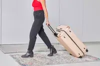 Person rolling the July Checked Plus Large Luggage across a rug