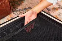 Hand inside a mesh pocket inside the July Checked Plus Large Luggage